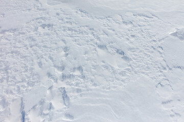 A snow covered ground with a few footprints