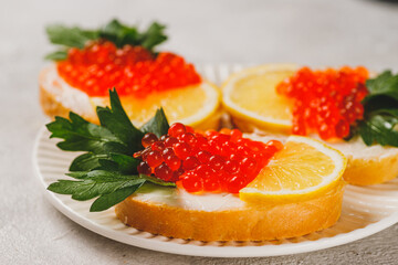 Sandwiches with red caviar, a slice of lemon, and a sprig of parsley