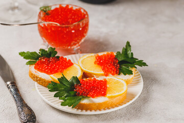 Sandwiches with red caviar, a slice of lemon, and a sprig of parsley