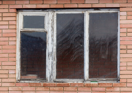A window with three panes of glass and a brick wall behind it