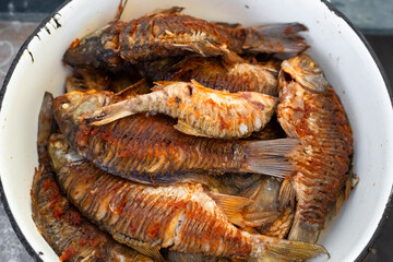 Fried crucian carp fish in an iron bowl on a picnic. Cooking outdoors