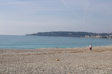 Woman walking in the Fossan beach along the Mediterranean sea, in Menton, France.