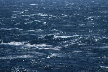 Naklejka premium vast ocean with turbulent waves creating dynamic seascape, showcasing power of nature. deep blue water contrasts with white foam, evoking sense of movement and energy