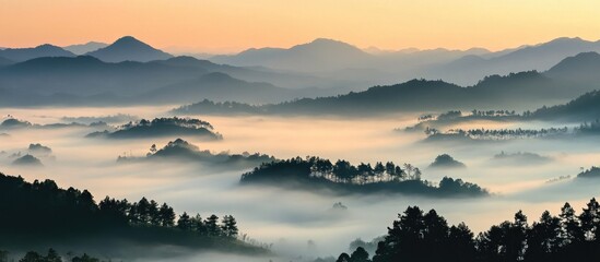Fototapeta premium Misty landscape at sunrise showcasing rolling hills and valleys enveloped in fog and serene mountain backdrop in tranquil nature scene.