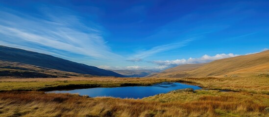 Fototapeta premium Serene mountain landscape under a clear blue sky with a tranquil pond reflecting the scenery suitable for wallpaper backgrounds