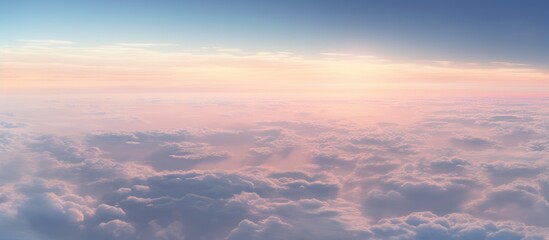 Obraz premium Serene aerial view of fluffy clouds under a pastel sky captured from an airplane window at sunset
