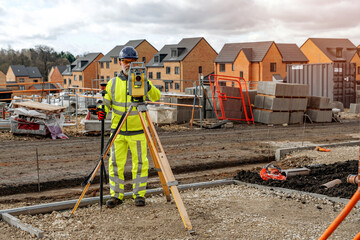 Construction engineer using survey equipment on a building site in a new housing development