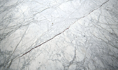 Fototapeta premium Close-up shot of white marble texture with a prominent crack, showcasing intricate veining and natural stone details. Ideal for design and architectural projects.