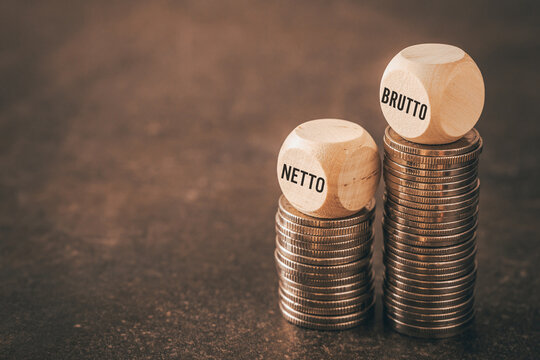 Netto and brutto. Net and gross symbol. Words on wooden cubes set on smaller and larger stack of coins change net to gross. Financial concept, dark wooden background, copy space