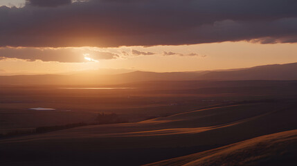 Serene sunset over rolling hills and distant plains, bathed in warm golden light. A breathtaking landscape photograph perfect for travel, nature, or serenity themes.