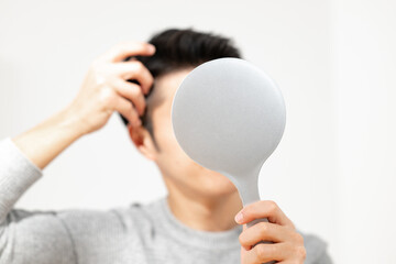 鏡を見て髪を気にする男性