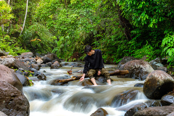 Man enjoy the serene of nature. Young man enjoying the river stream.