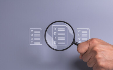 Hand and magnifying glass focus on document on gray background, Analysis and verification of business data, Check documents