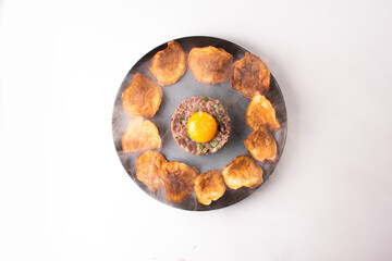raw meat tartar dish hackepeter raw egg seasoned spices with and smoked potato chips with smoke sweet fries top view white background