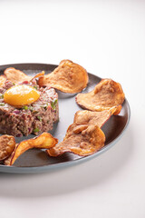 plate of hackepeter tartare of raw meat with raw egg yolk and spices and rustic potatoes CLOSE UP