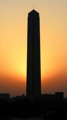A tall building silhouetted against a vibrant sunset, creating a dramatic skyline.