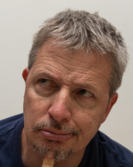 Portrait of a middle-aged man with striking gray hair, gazing directly at the camera with a serious and contemplative expression, reflecting deep thought