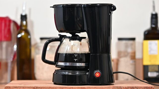 A coffee machine brewing some medium roasted coffee powder for breakfast on a piece of rustic wood.