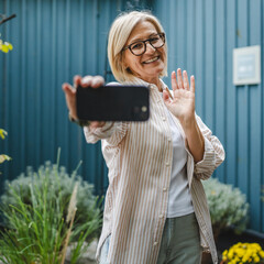 mature woman stand in front restaurant and have video call