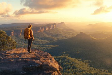 Obraz premium Adventurous Hiker Enjoys Scenic View from a Rocky Outcrop During a Vibrant Sunrise Over Lush Green Mountains and Expansive Valley Landscape