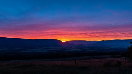 Obraz premium Vibrant sunrise over mountain range and valley.