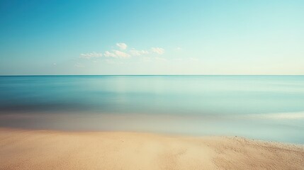 Serene beach landscape with calm ocean and sandy shore under a clear blue sky.