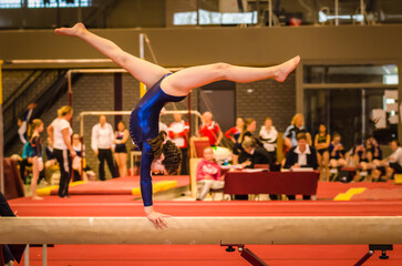 Young gymnast girl performing routine on balance beam