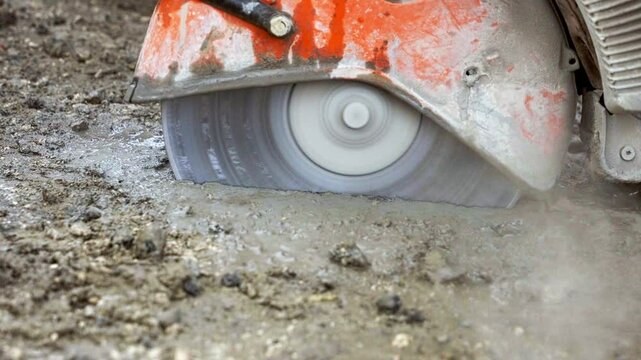 Cutting through wet asphalt with petrol power sam and dimond blade for new electric duct installation