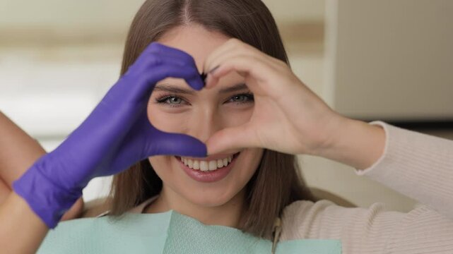 Doctor and patient are doing heart with hands in office. The doctor is grateful for the trust