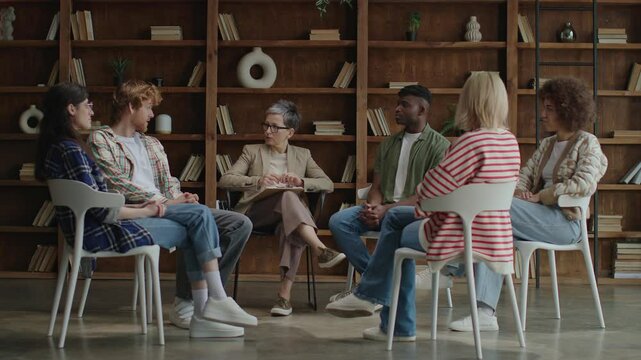 In a contemporary setting, six diverse young adults convene in a circle for a therapeutic session, fostering growth and solidarity