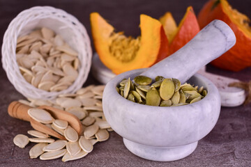 Pumpkin seeds in shell and peeled on a dark background.
