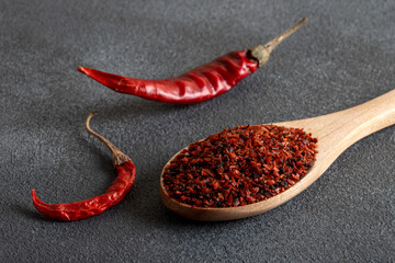 Red pepper flakes.Red chili peppers in wooden spoon on gray background.Dried chili peppers