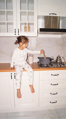 Little chef is sitting on the kitchen table and cooking dinner . High quality photo