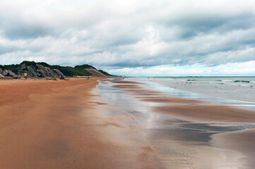 A beach with a cloudy sky in the background
