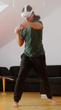 Person is deeply engaged in gaming with a VR headset in a living room. Man practices virtual boxing