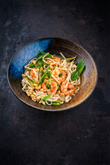 Authentical Asia style ramen noodle soup with prawns and cashew nuts served as close-up in a design bowl