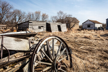 Obraz premium A wheel is sitting in the dirt next to a barn