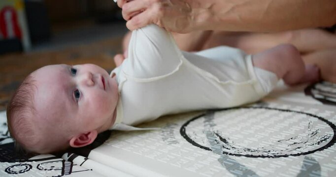 Newborn baby is lying floor mat and playing with his mom. mother is playing with her newborn baby in the nursery. Concept of children, child, parenthood
