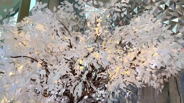 4K footage of christmas decoration, trees, tinsels, slingers hanging from ceiling. Walking through christmas decoration to celebrate seasons greetings, seen the white themed leaves, trees, and silver 