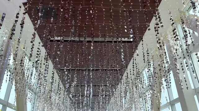 4K footage of christmas decoration, trees, tinsels, slingers hanging from ceiling. Walking through christmas decoration to celebrate seasons greetings, seen the white themed leaves, trees, and silver 