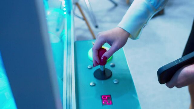 Hobbies and entertainment. Young woman plays slot machine crane. Female hand controls joystick and presses button. Close-up.