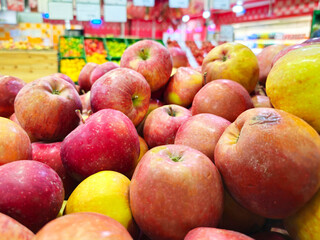 Red ripe apples on the counter in the supermarket. Many apples in the foreground, against the background of different products.