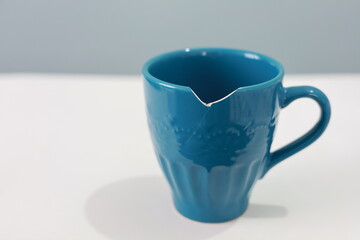 A broken blue cup on blue background