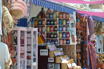 Market stall in Essaouira displaying vibrant pigments, spices, and handmade sandals under colorful awnings, highlighting the richness of Moroccan crafts and local products
