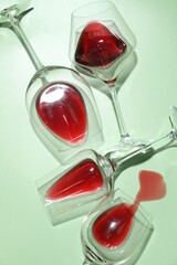 Glasses of red wine on light green background, flat lay