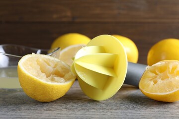 Plastic juicer and fresh lemons on grey wooden table, closeup