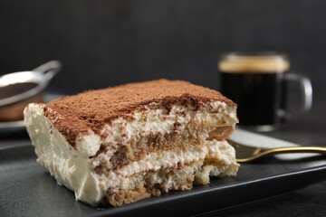Piece of tasty tiramisu on black table, closeup