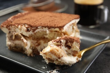 Eating tasty tiramisu at black table, closeup