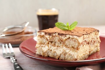 Delicious tiramisu with mint on light wooden table, closeup