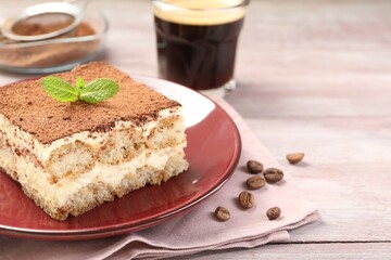 Plate with delicious tiramisu, mint and coffee beans on wooden table, closeup